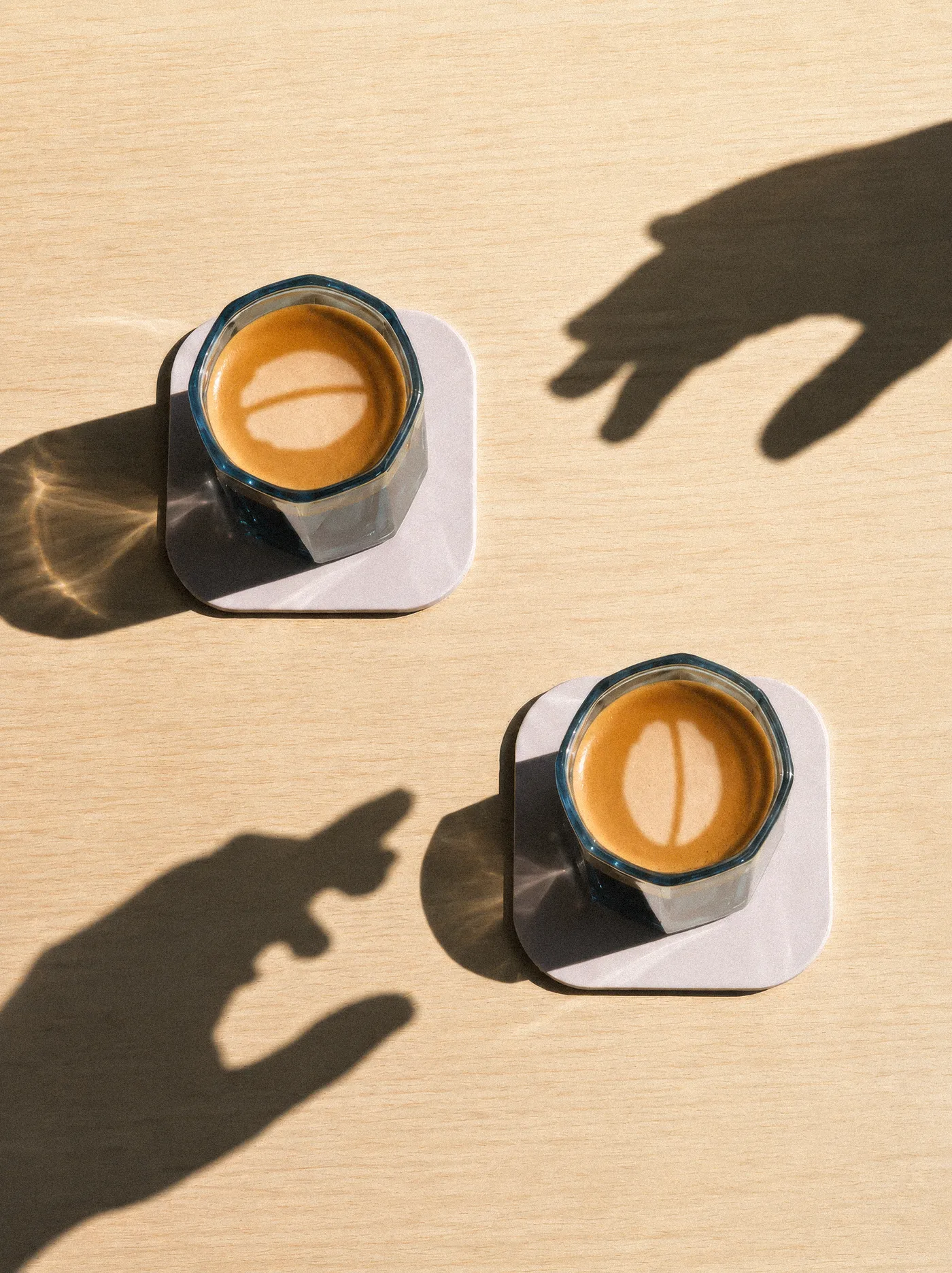 Two flat whites with the Idle Hands bean in the crema and long hand shadows reaching across the table