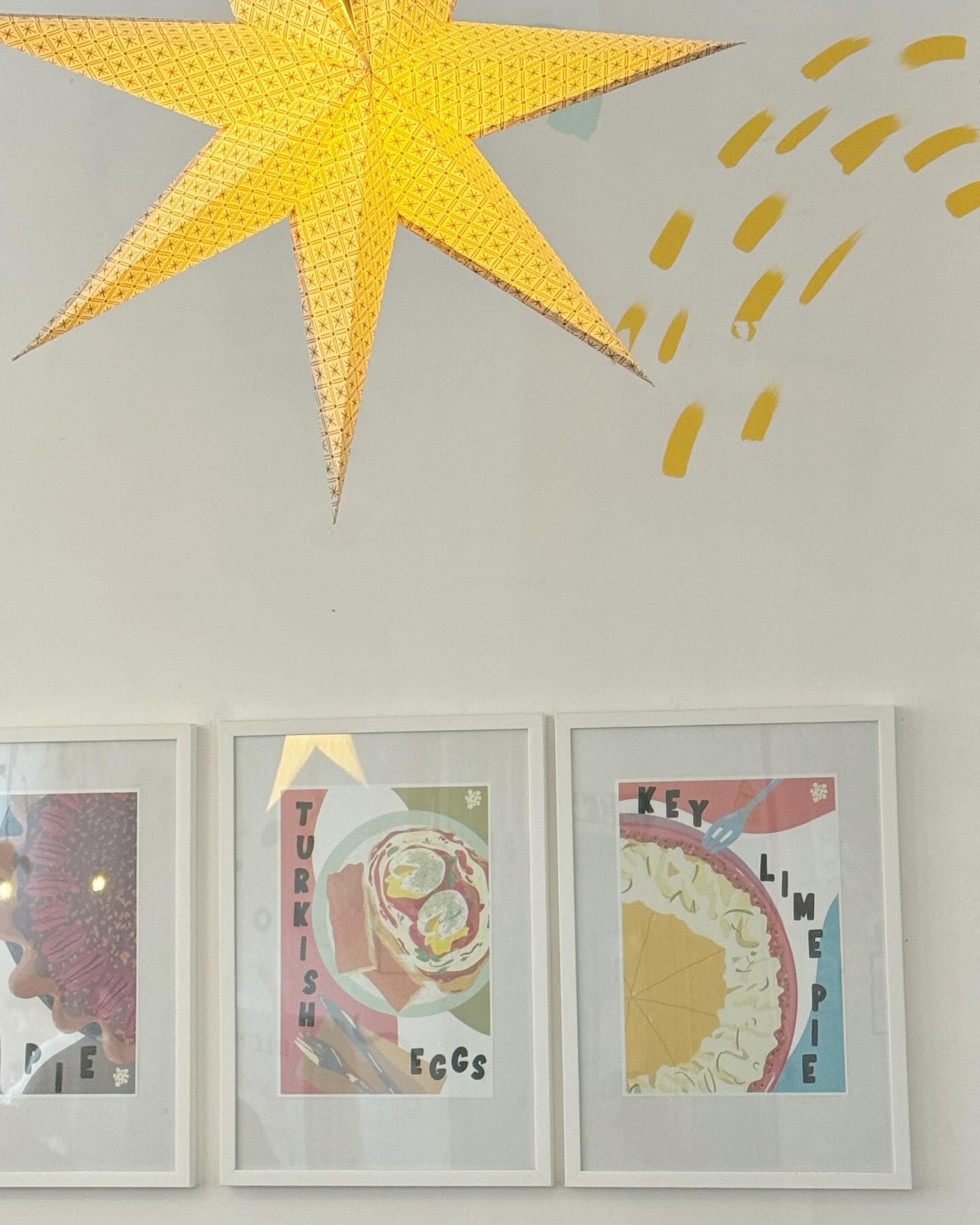 A paper star lantern hanging over framed pie and brunch posters inside Idle Hands